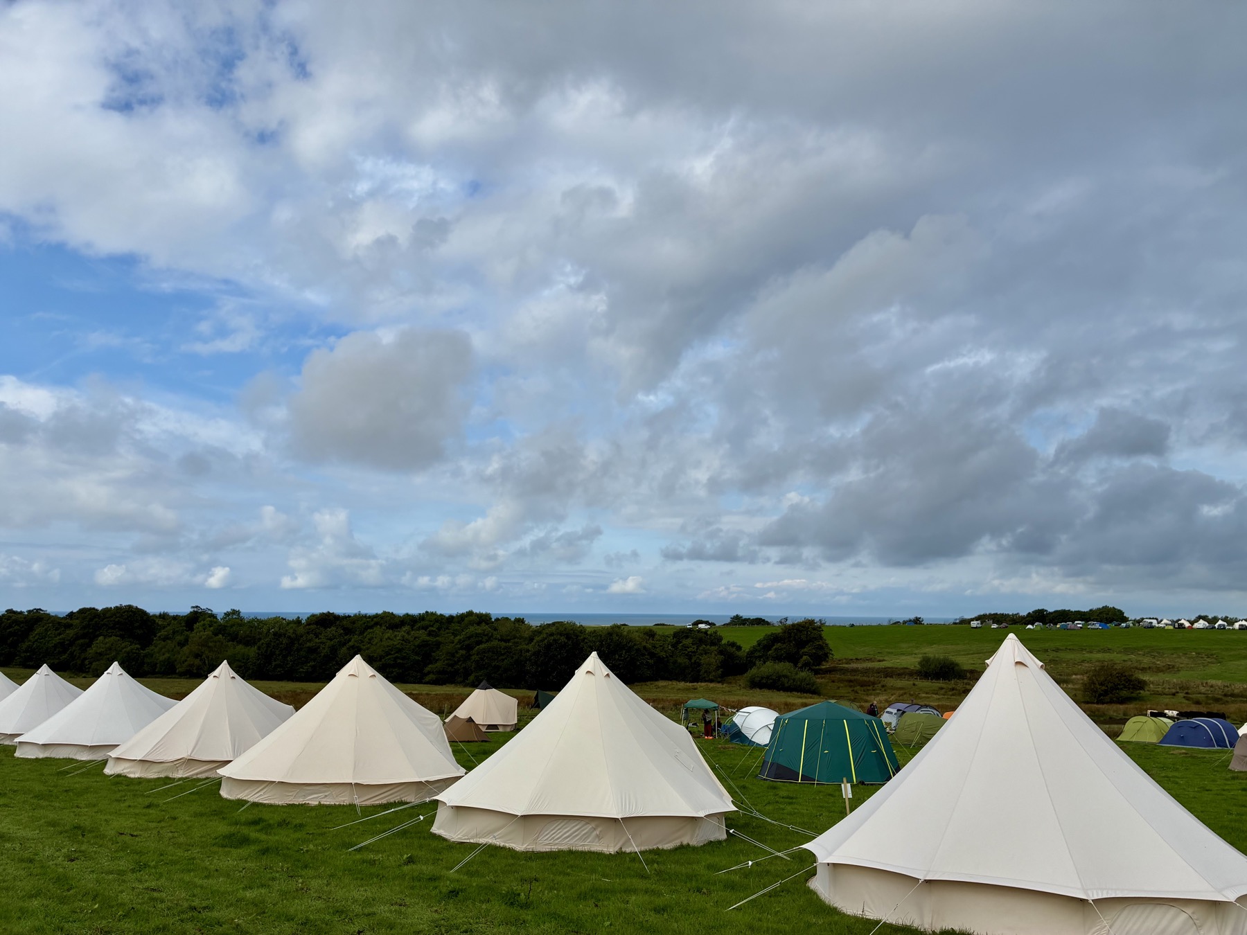 Row of bell tents at Muncaster Castle with the Irish Sea on the horizon